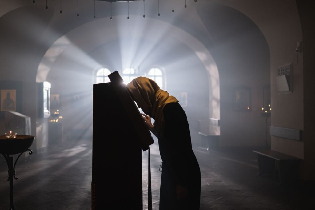 A woman praying by a window illustrates the power of prayer in cultivating strength in the Lord