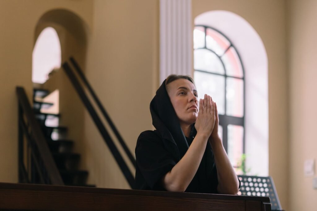 A woman praying by a window, illustrating the power of prayer in seeking courage and strength