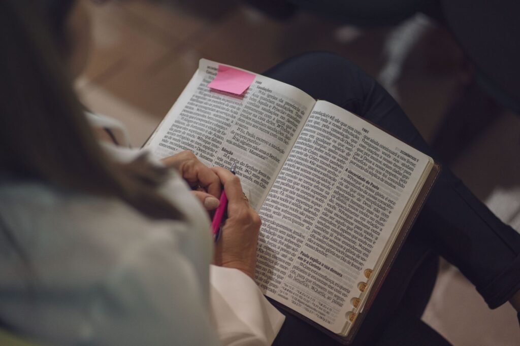 A woman reading a Bible with a pink note, captured indoors showing devotion and study