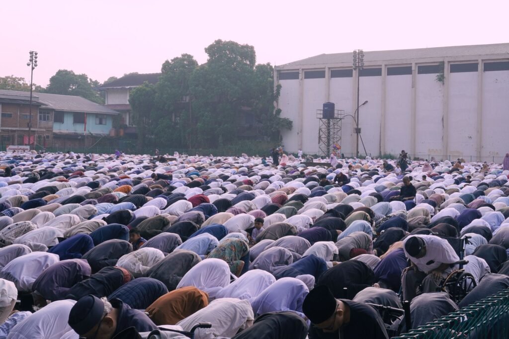 Large group of people gathered outdoors for prayer at dusk